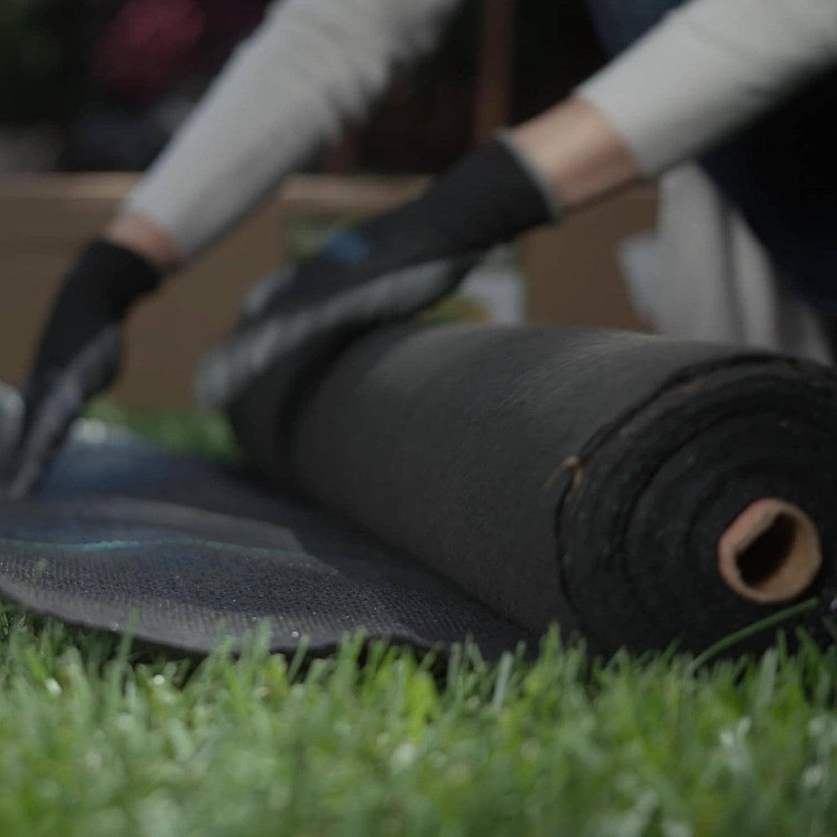 Close-up of black weed barrier fabric roll edge, showing textured weave and thickness.
