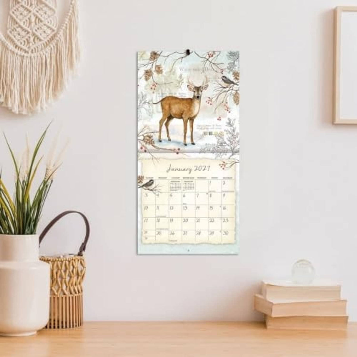 Mini wall calendar hanging on a wall, showing a deer-and-bird January 2017 page