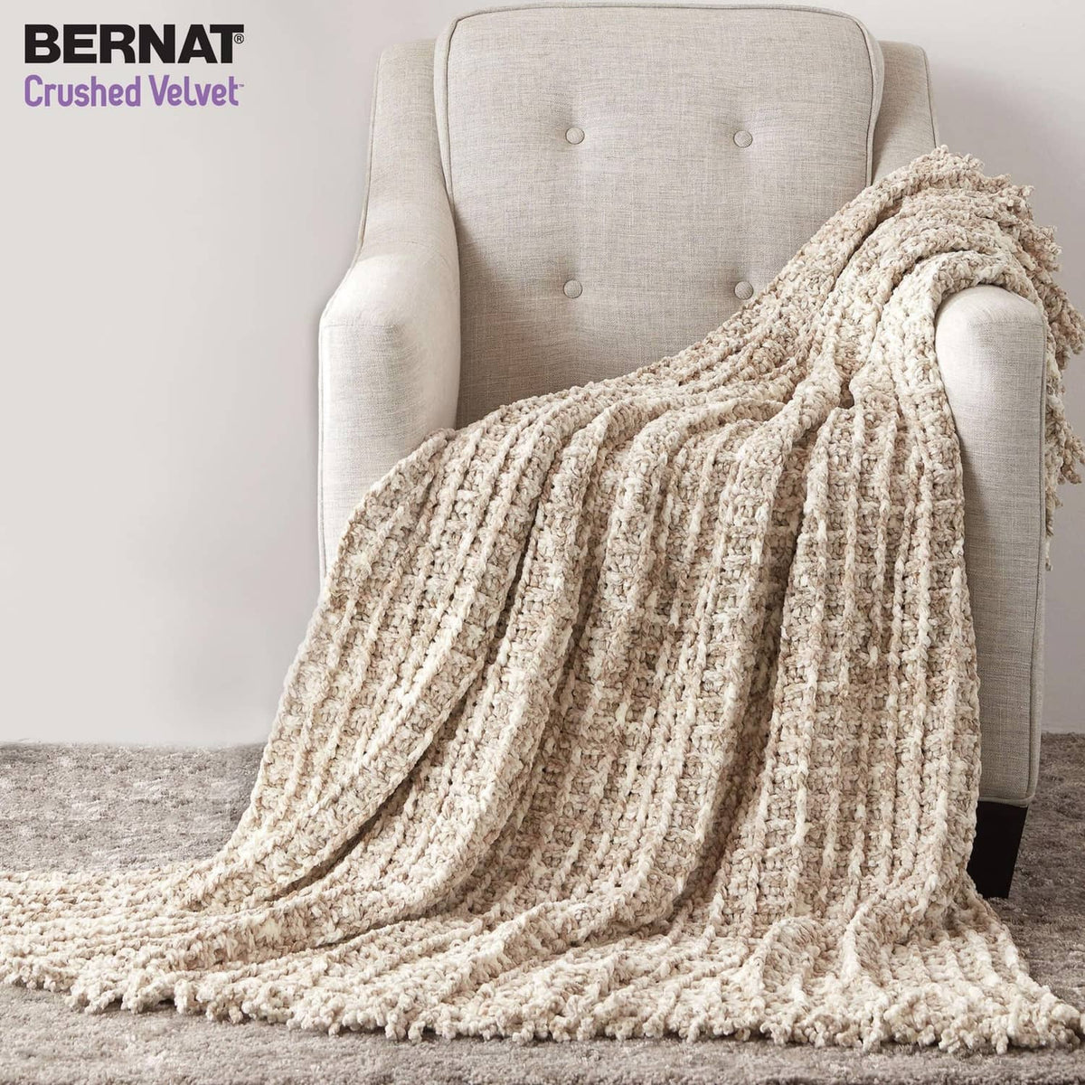 Cream chunky knit throw blanket draped over a light upholstered chair.