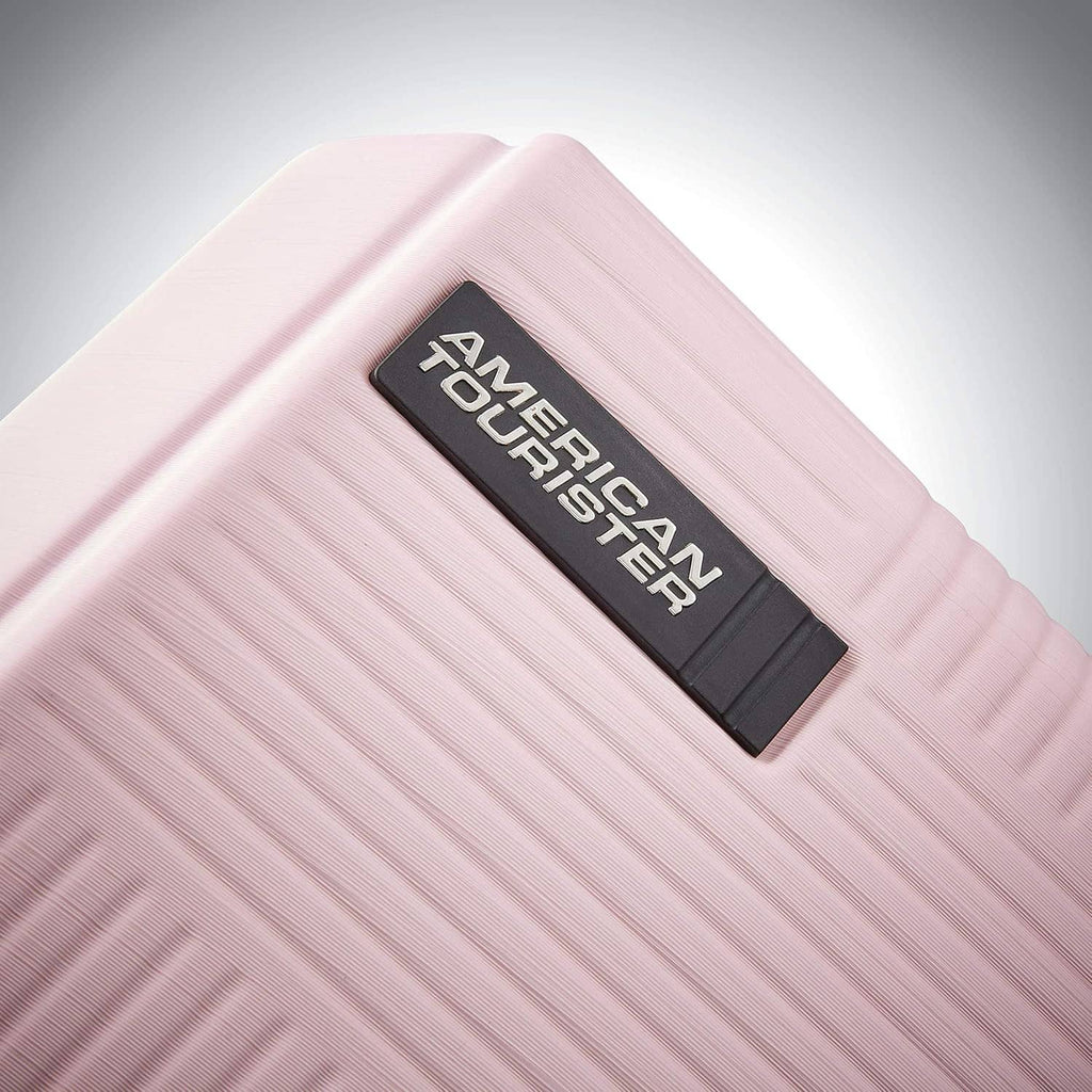 Pink hard-shell luggage front panel with black American Tourister ID label