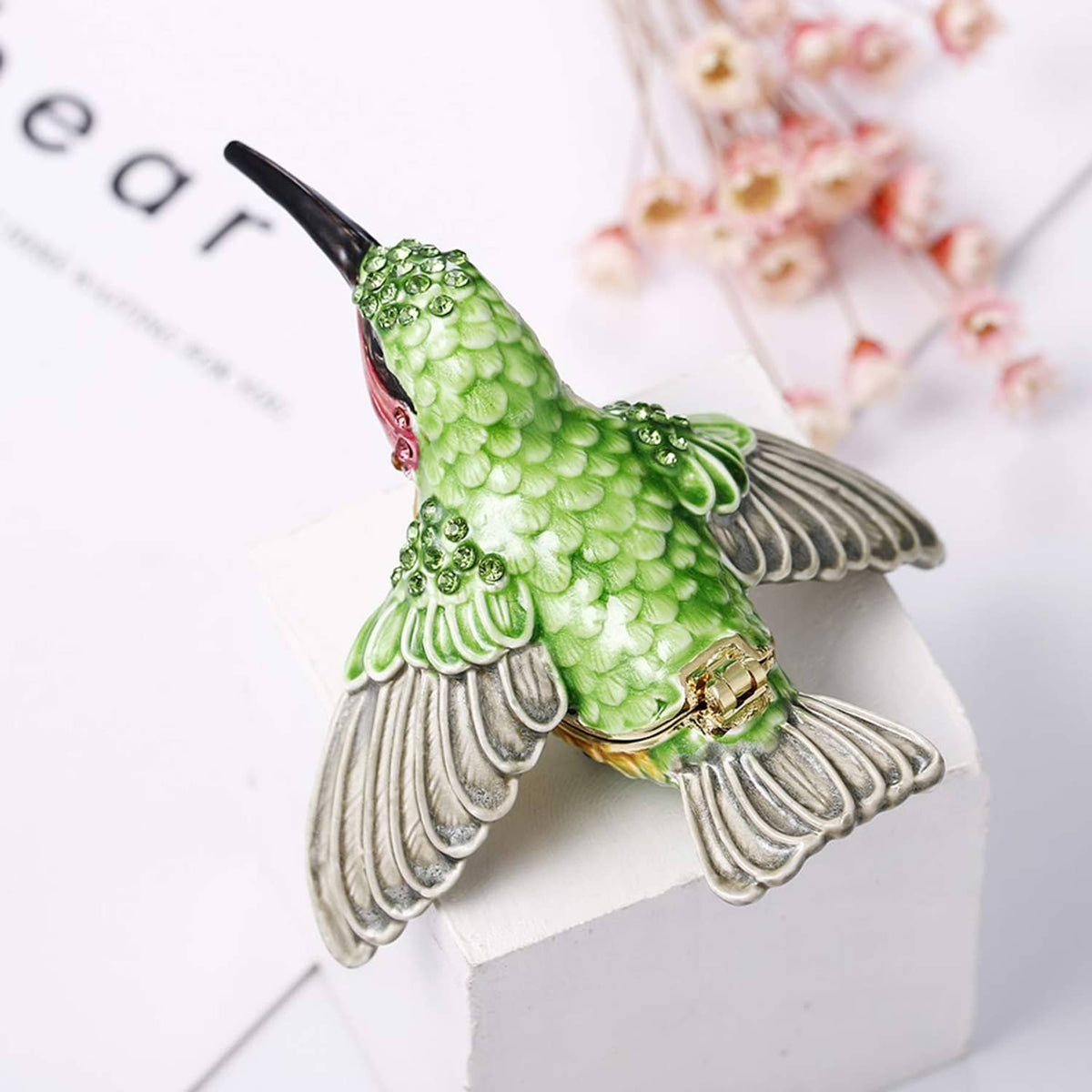 Hand-painted enamel hummingbird trinket box with green body and silver wings, hinged lid