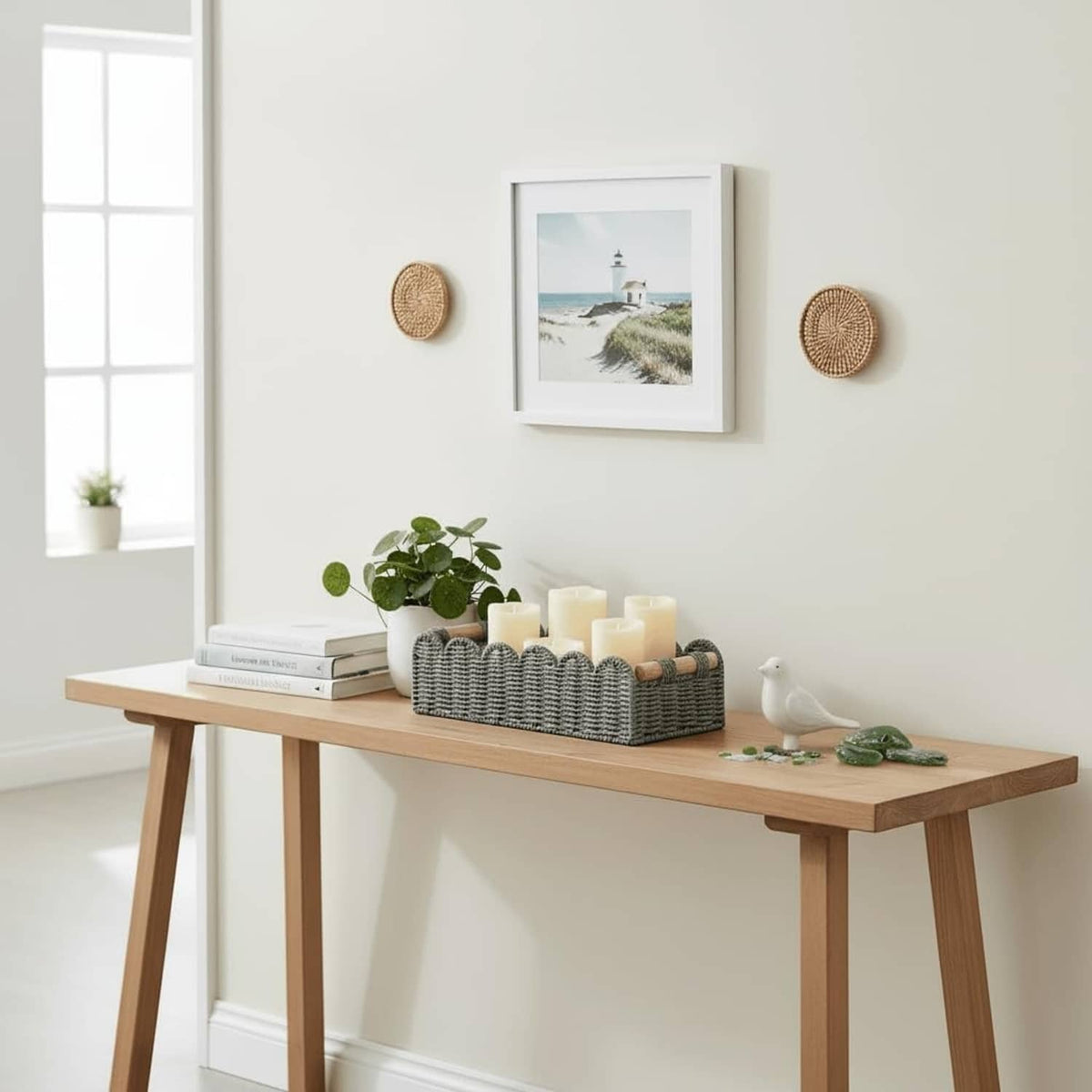 Grey woven toilet paper storage basket with scalloped rim and wood handles on a tabletop.