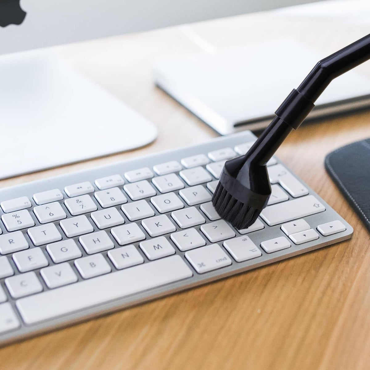 Black micro brush nozzle cleaning a computer keyboard key area