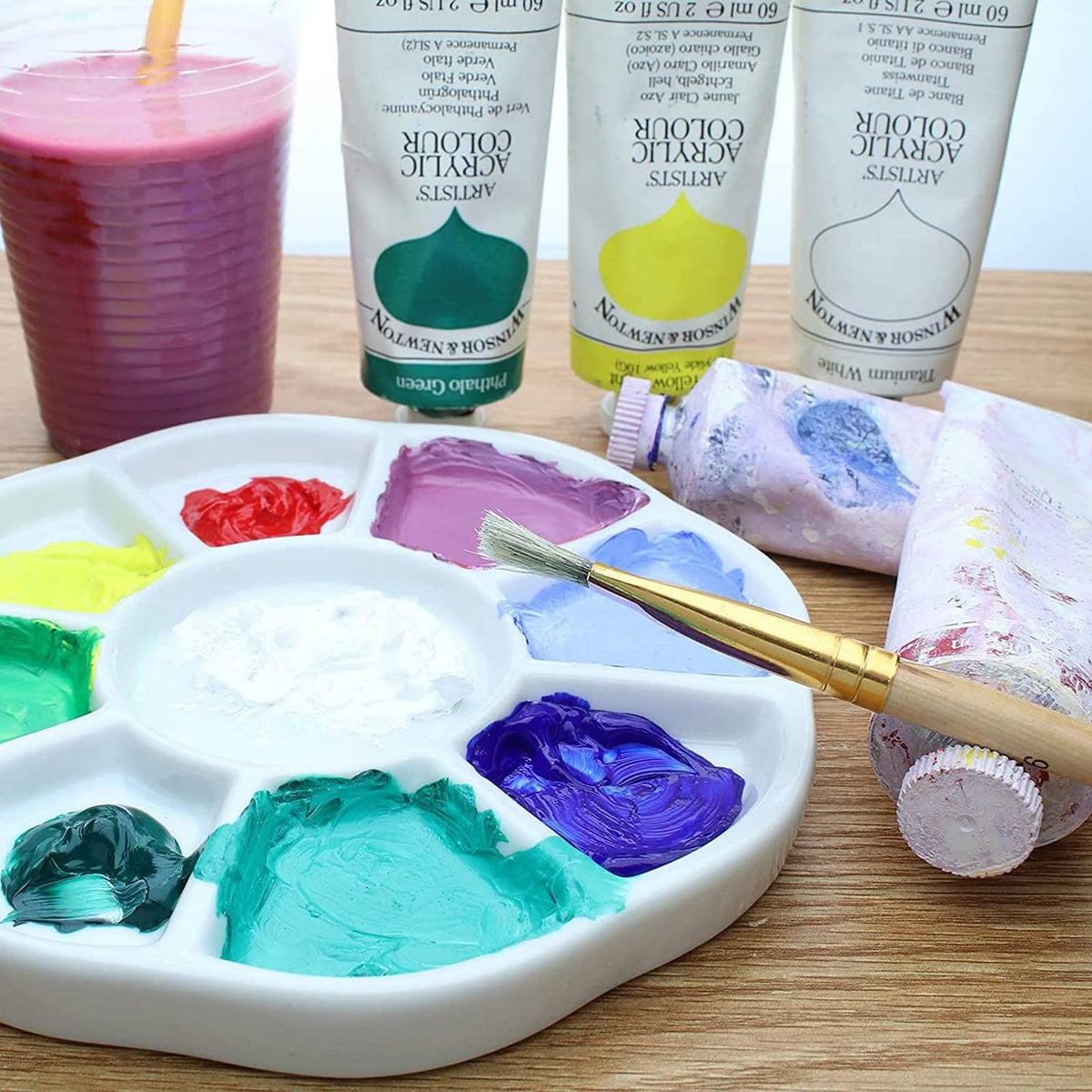 White 9-well watercolor paint palette with colorful paint blobs and brush
