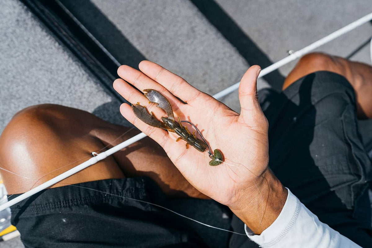 Hand holding multiple lime green craw lures with dark speckles