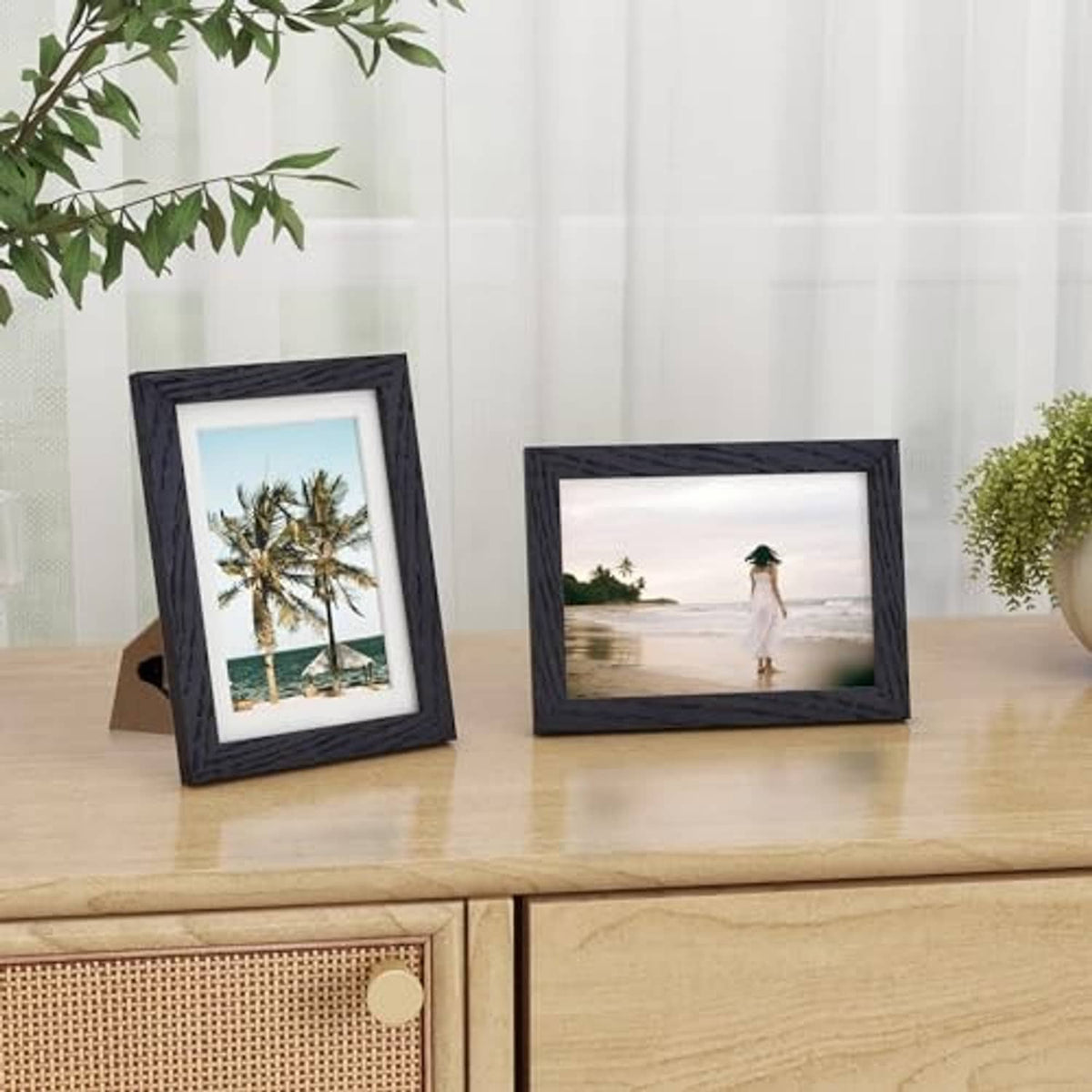 Two black 5x7 picture frames standing on a table, each with a photo