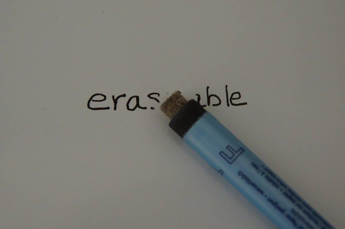 Fine-point correction pen tip touching paper, light-blue barrel with black nib