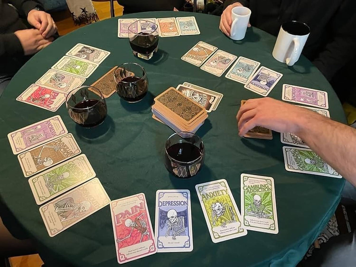 Side Effects card game on table with player hands and face-up condition cards