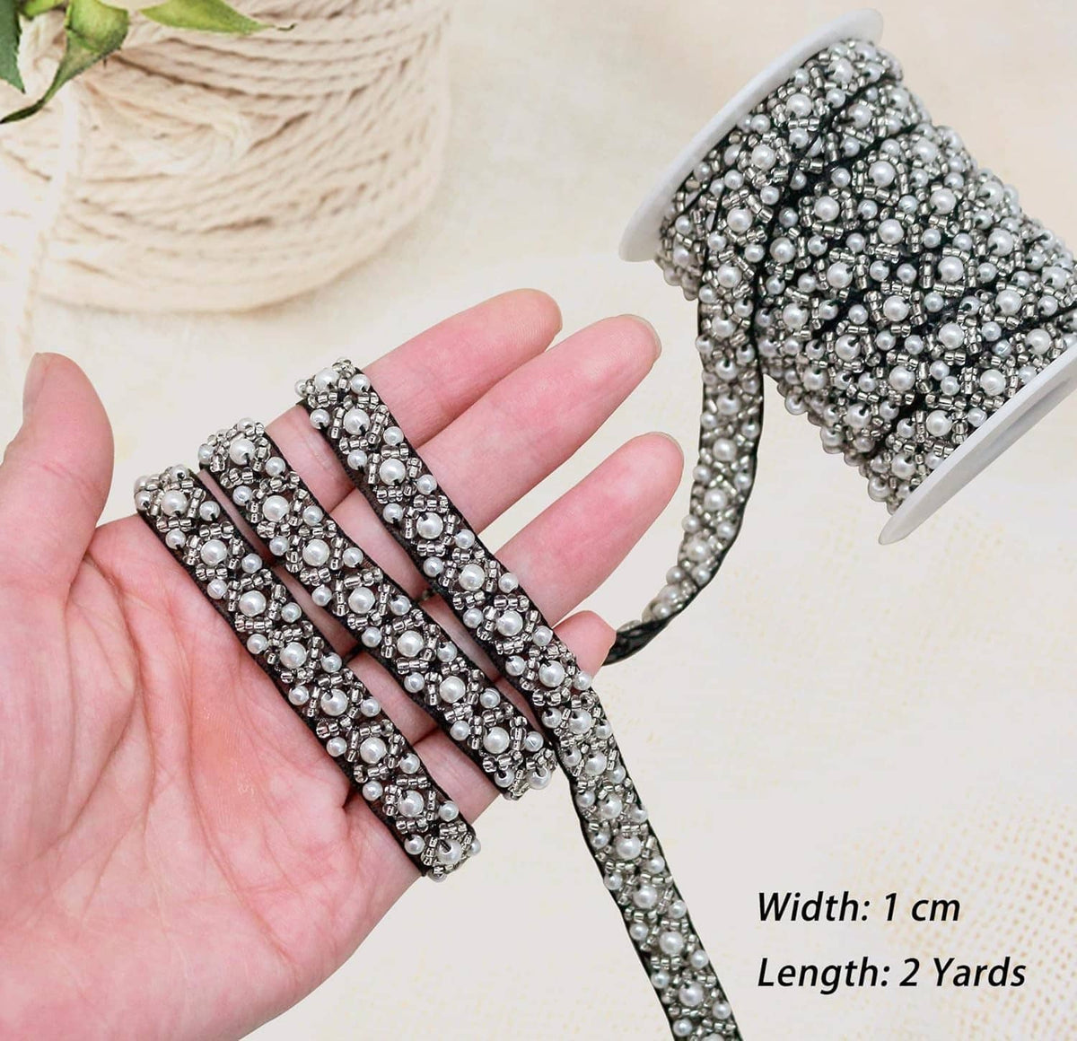 Pearl beaded lace trim ribbon held in hand, black base with silver-white pearls