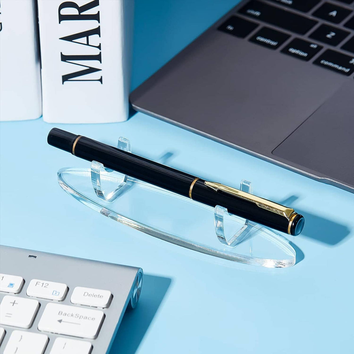 Clear acrylic pen holder tray holding a black and gold pen on desk