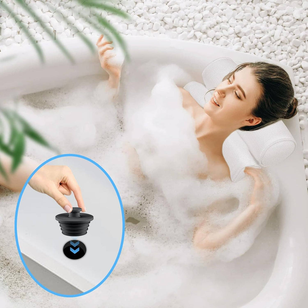 Hand pressing a dark gray silicone drain stopper into a bathtub drain opening