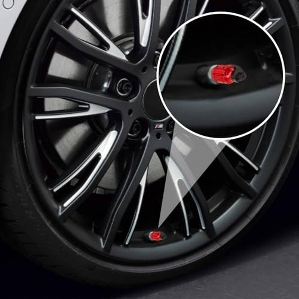 Close-up of red lantern-style tire valve stem cap with black cap ring on a wheel.