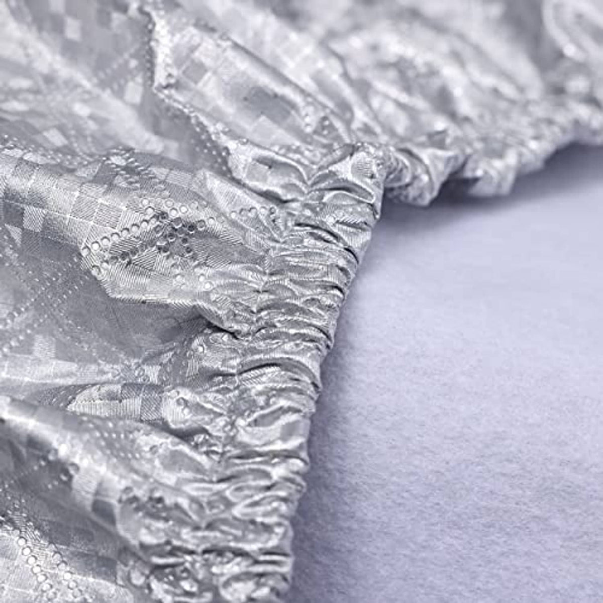 Close-up of silver tire cover fabric with wrinkled aluminum-style surface and stitched edge