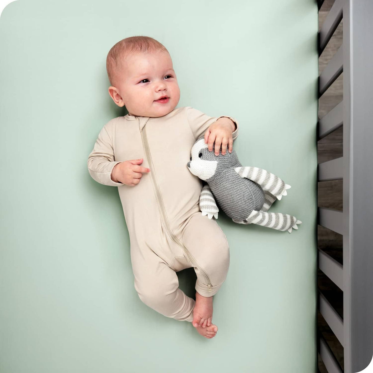 Mint green fitted crib sheet covering mattress, smooth fabric with snug corners