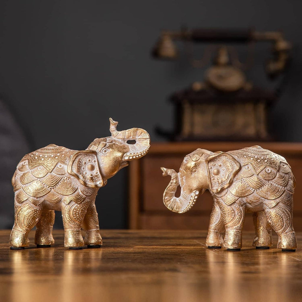 Two gold elephant figurines with raised trunks, side-by-side decorative stance.