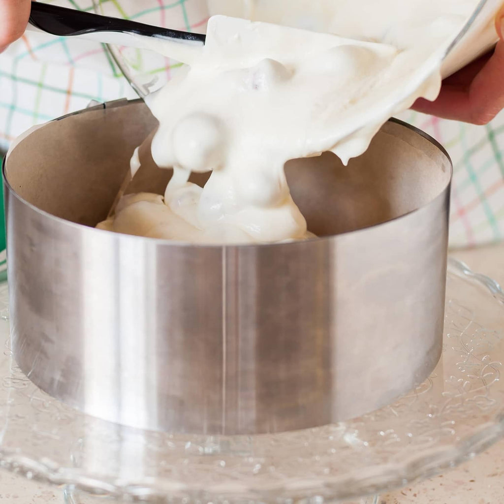 Stainless steel round cake ring holding cake filling with frosting on top
