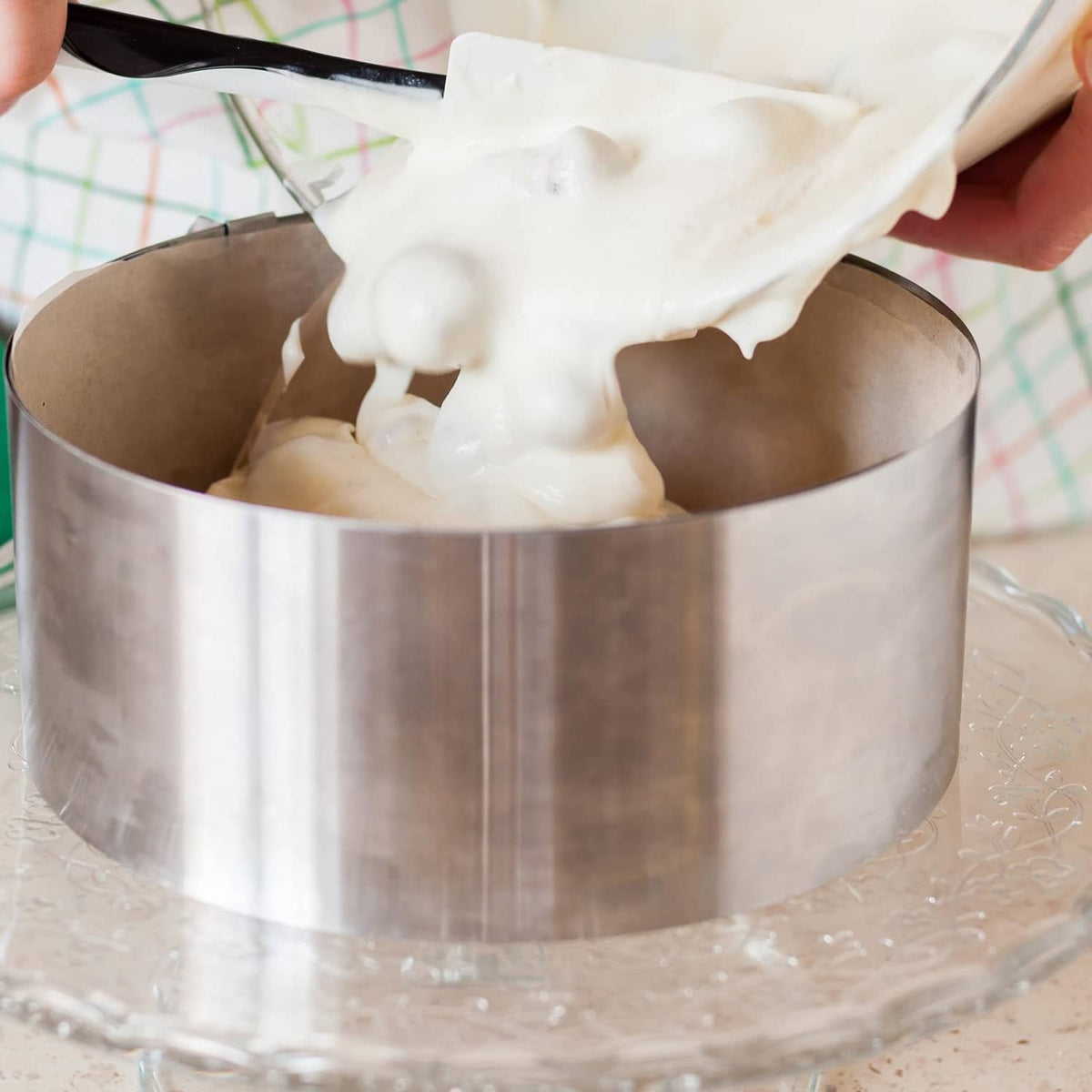 Stainless steel round cake ring holding cake filling with frosting on top
