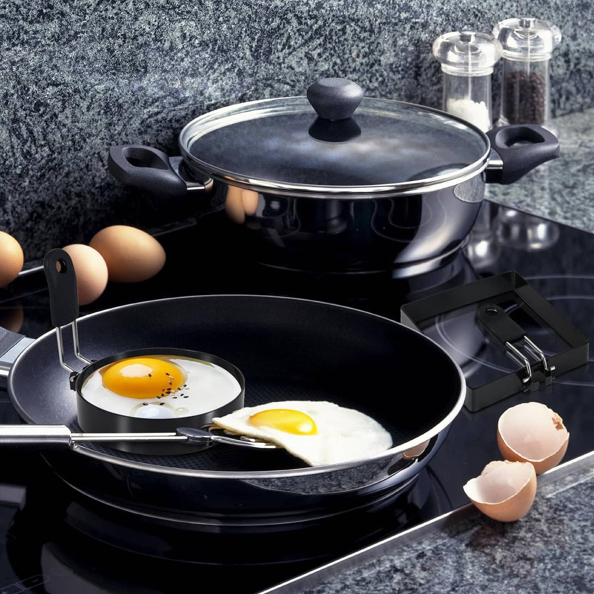 Black egg rings in a frying pan, round and square molds with two sunny-side eggs