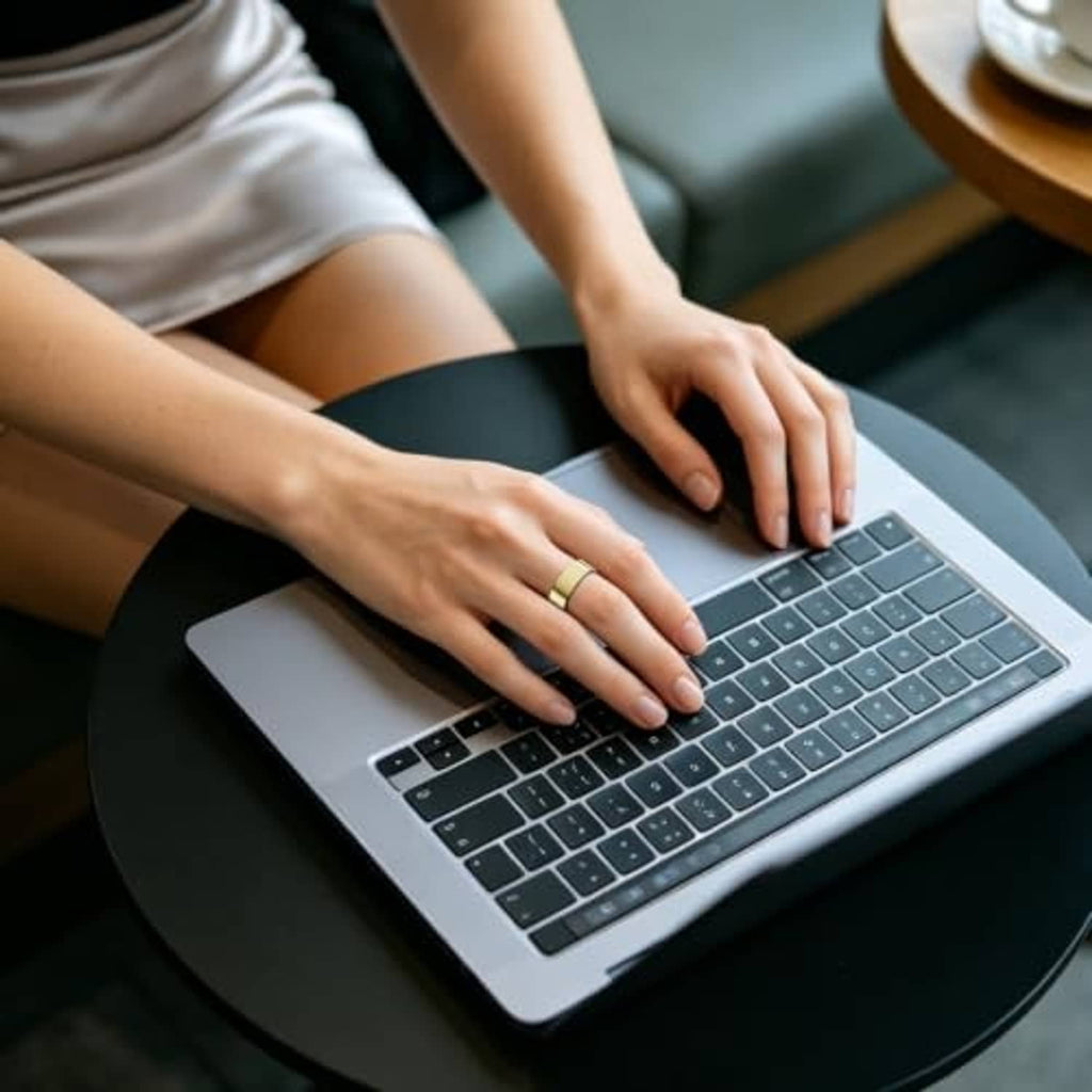 Gold ring cover on hand typing on laptop keyboard, slim band