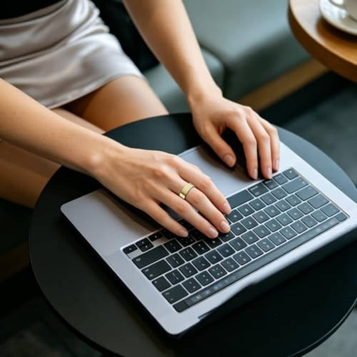 Gold ring cover on hand typing on laptop keyboard, slim band