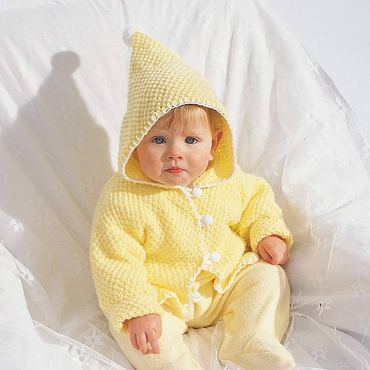 Baby in light yellow knitted hat and matching sweater outfit