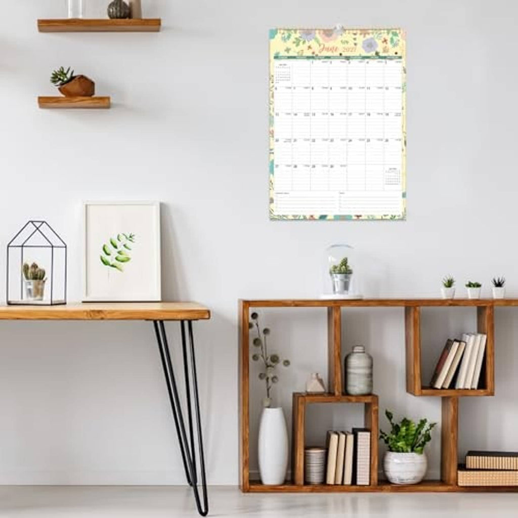 Floral wall calendar hanging on a wall in a home setting, with monthly planning grid