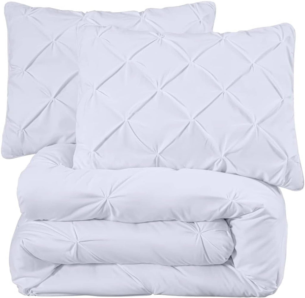 Folded white king comforter with matching quilted pillow shams featuring diamond pinch pleats