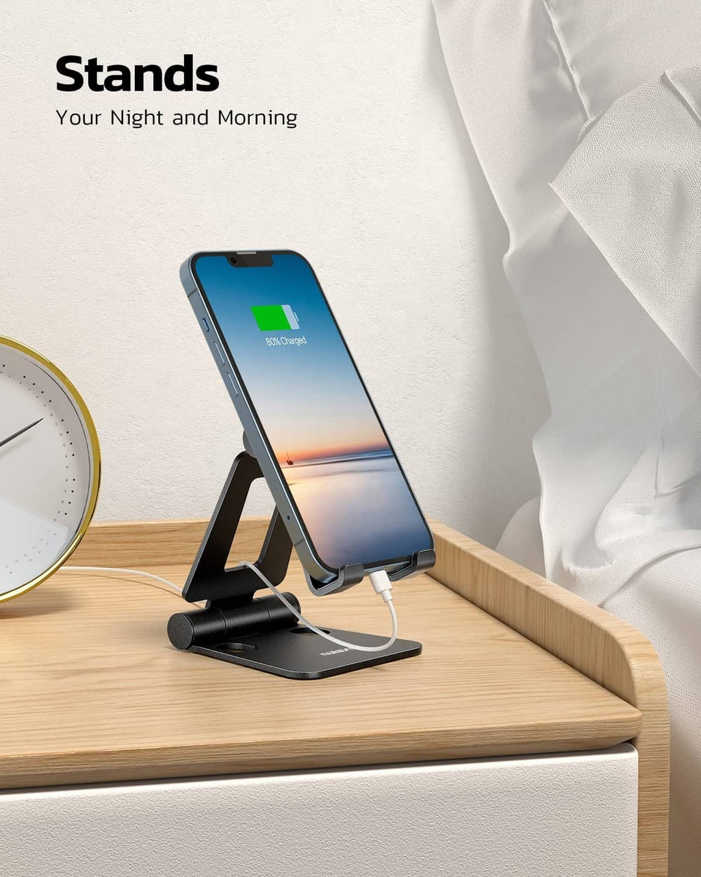 Black foldable phone stand holding a smartphone on a stable tabletop base
