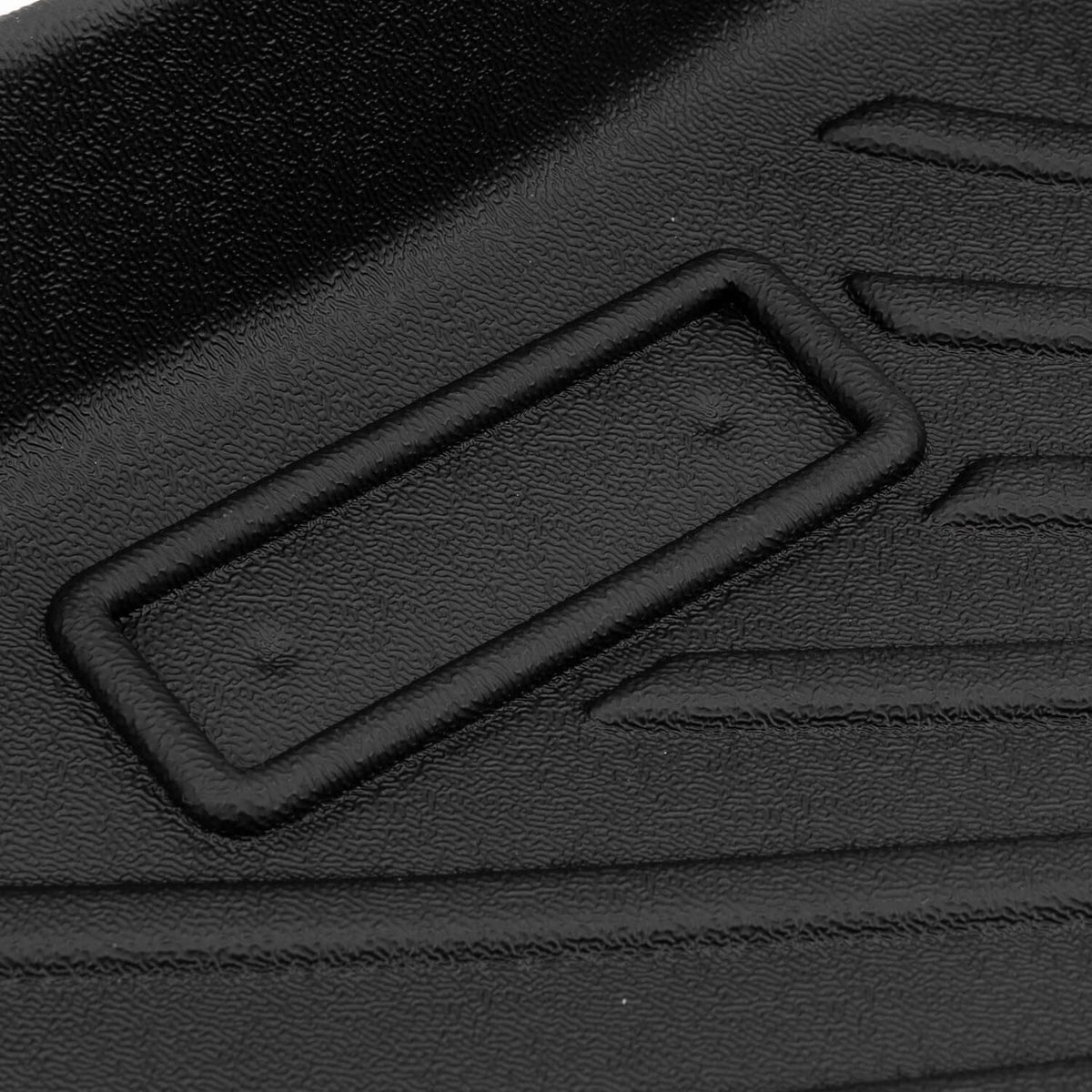 Black floor mat with molded rectangular retention grip and surrounding raised border.