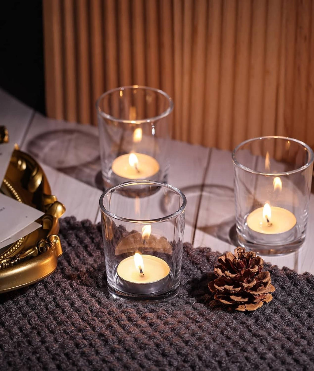 Set of clear glass tea light holders with lit candles and pinecone decor