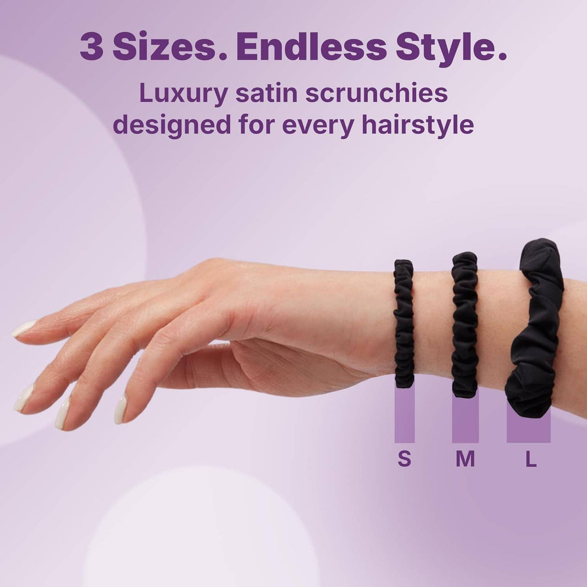 Hand wearing black satin scrunchies in multiple sizes on wrist