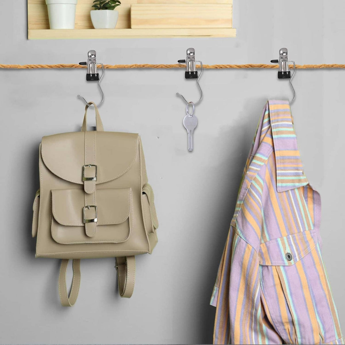 Boot hanger clips holding a beige bag and striped apron on a closet rod