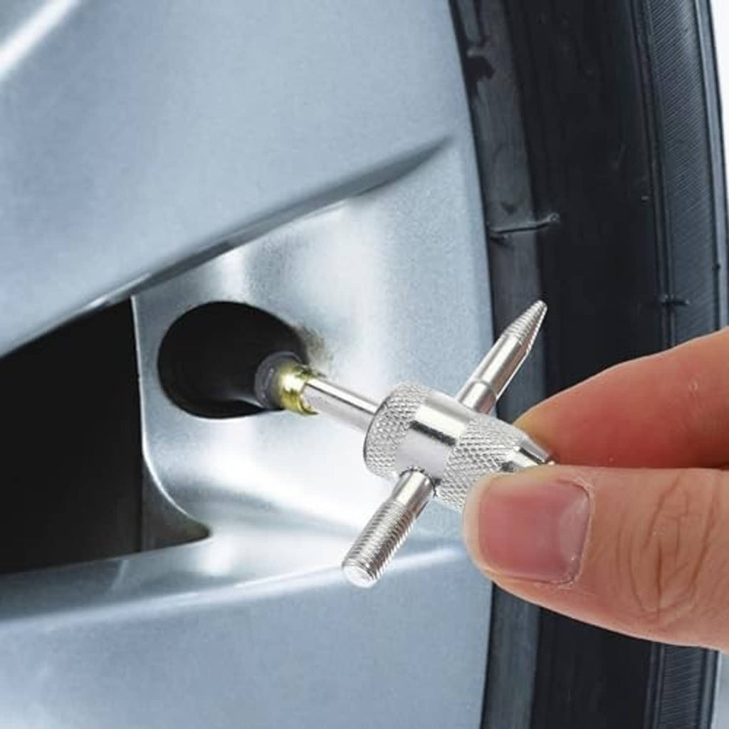 4-way tire valve core tool held at a car wheel valve opening
