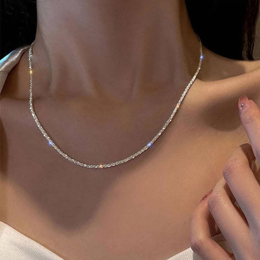 Close-up of layered silver-tone chains with small cross charm pendant at center