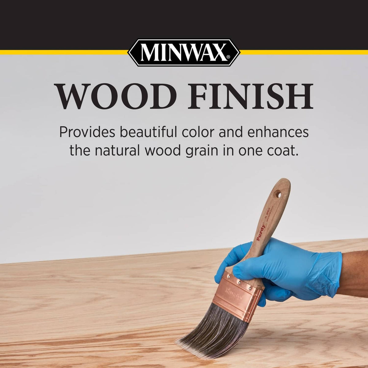 Hand applying wood finish stain to light wood tabletop with brush