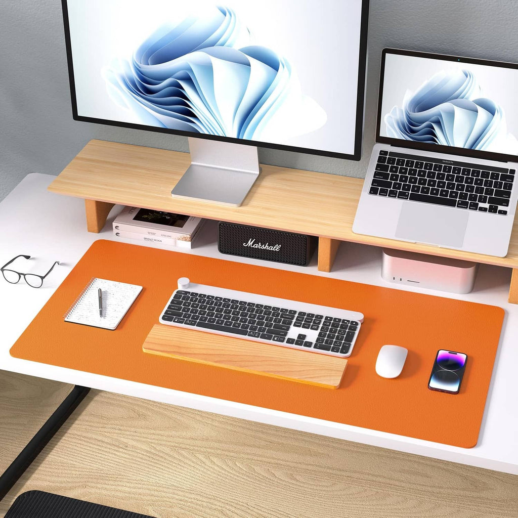 Orange leather desk pad protector on wooden desk with keyboard and computer setup