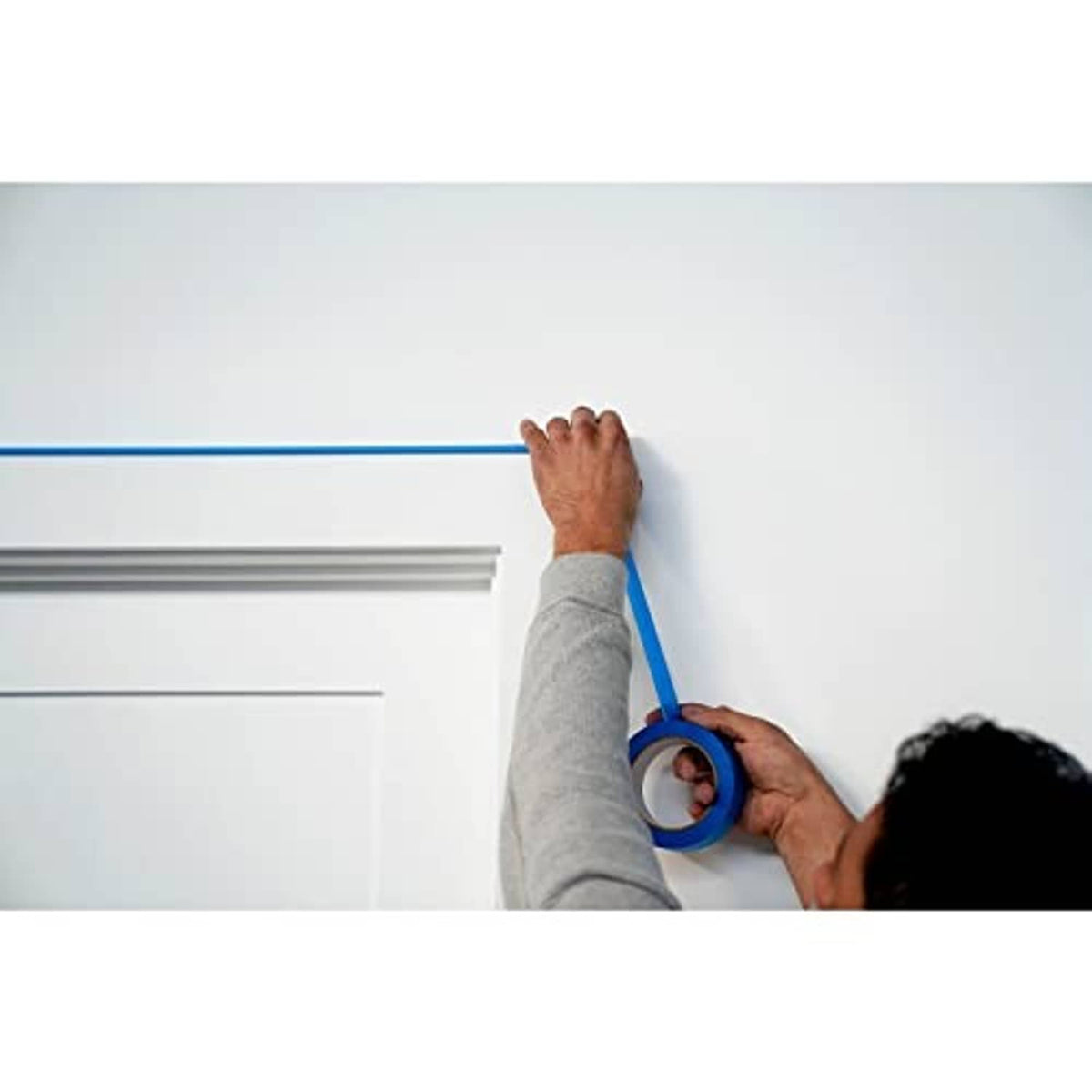Blue painter's tape strip applied along a wall and trim edge