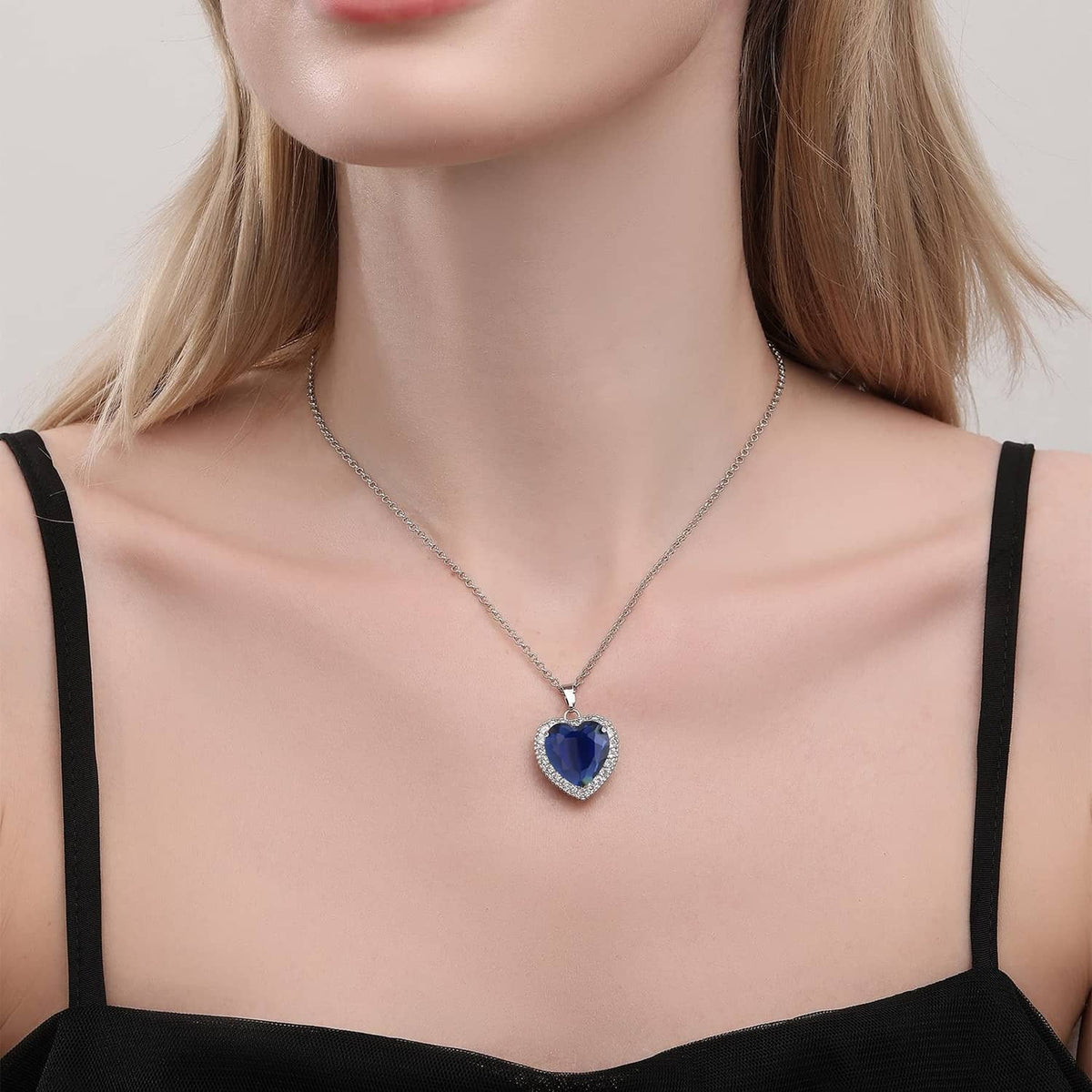 Blue heart pendant necklace with crystal border on silver chain, worn