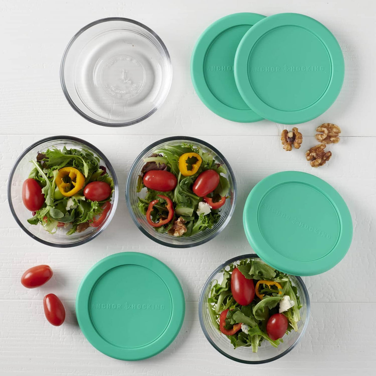Set of round glass food storage containers with teal lids, top view