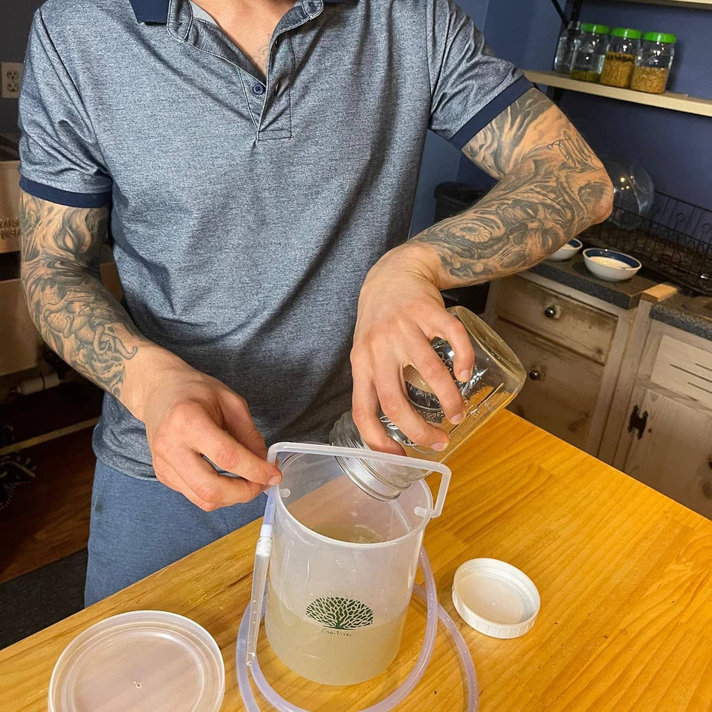 Clear enema bucket and hose shown being filled during setup at a kitchen counter