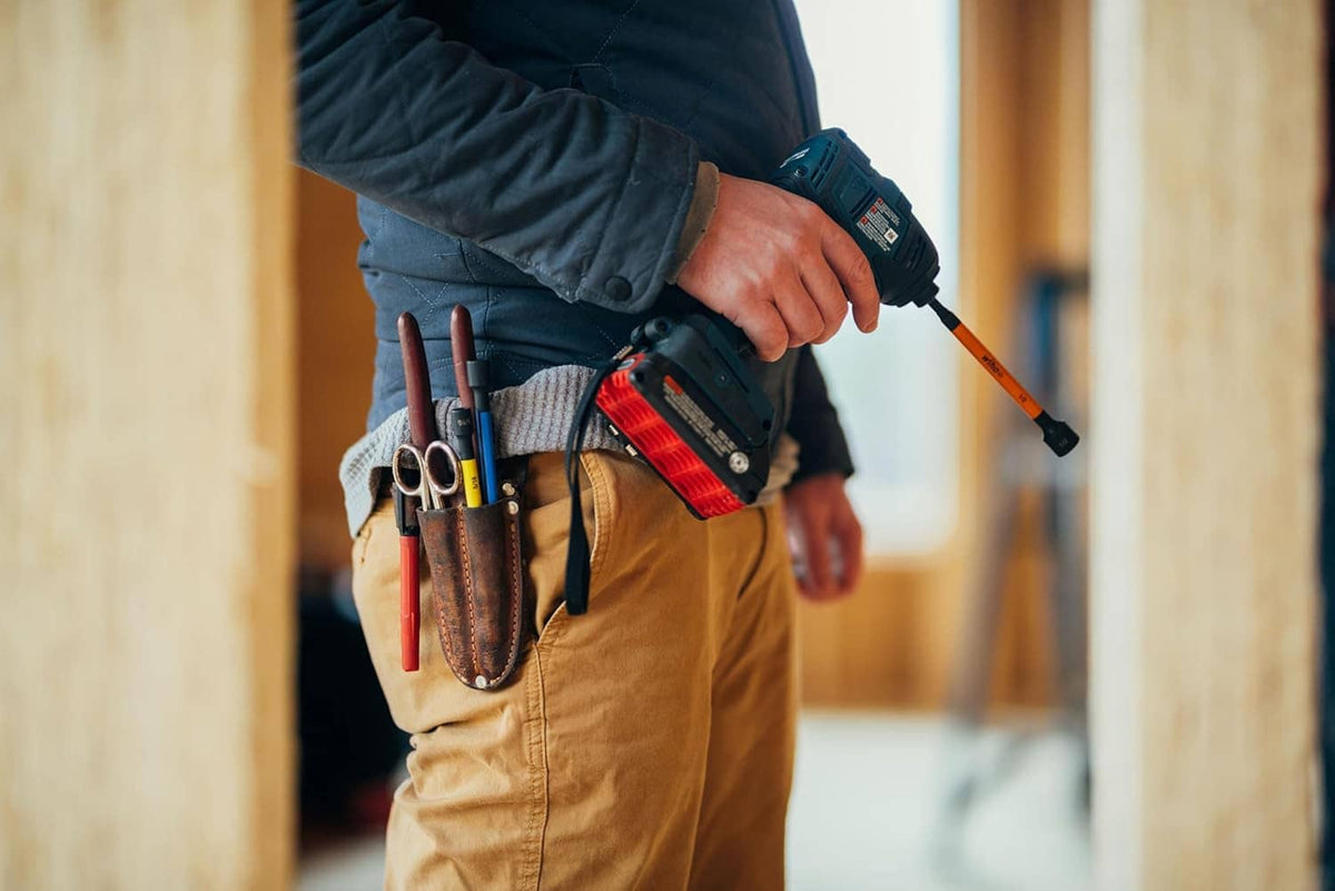 Magnetic nut setter bit attached to a cordless drill, held by a person outdoors