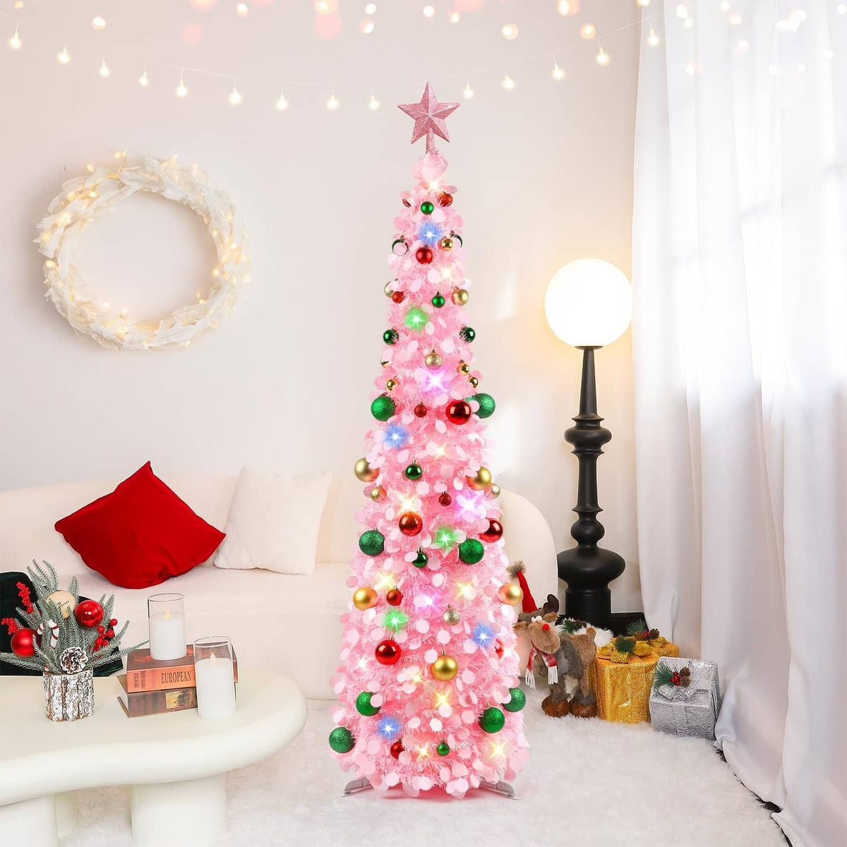 Pink lit Christmas tree with star topper and multicolor ornaments, standing upright