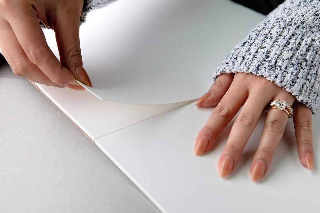 Hands placing and smoothing a white tracing paper sheet