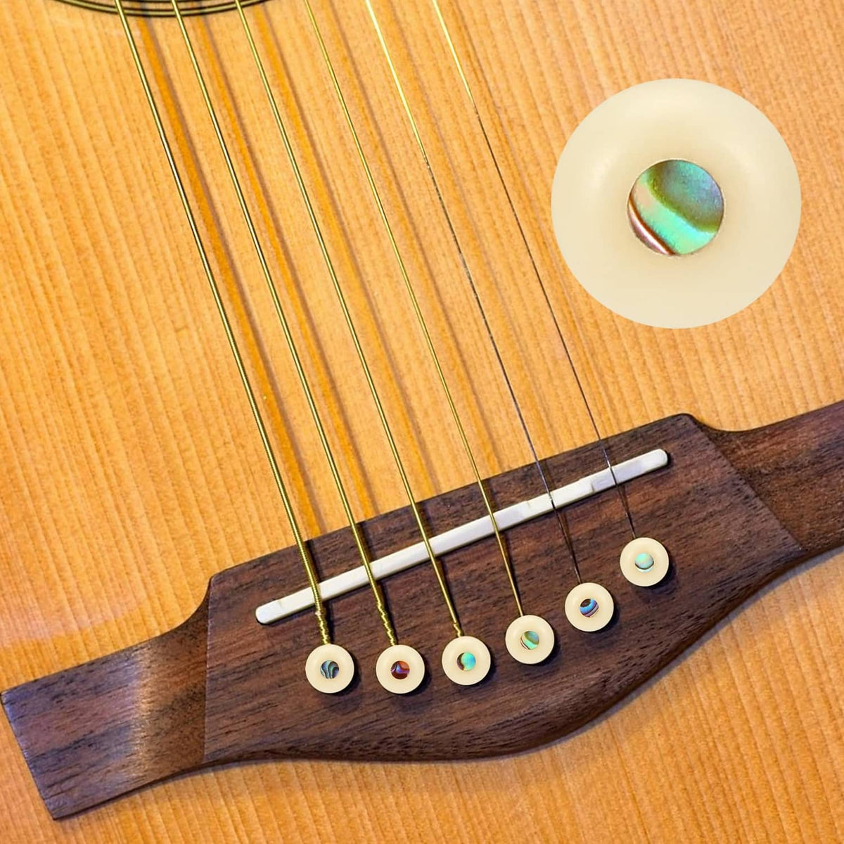 Guitar bridge pins with iridescent inlay caps on a wooden acoustic guitar bridge