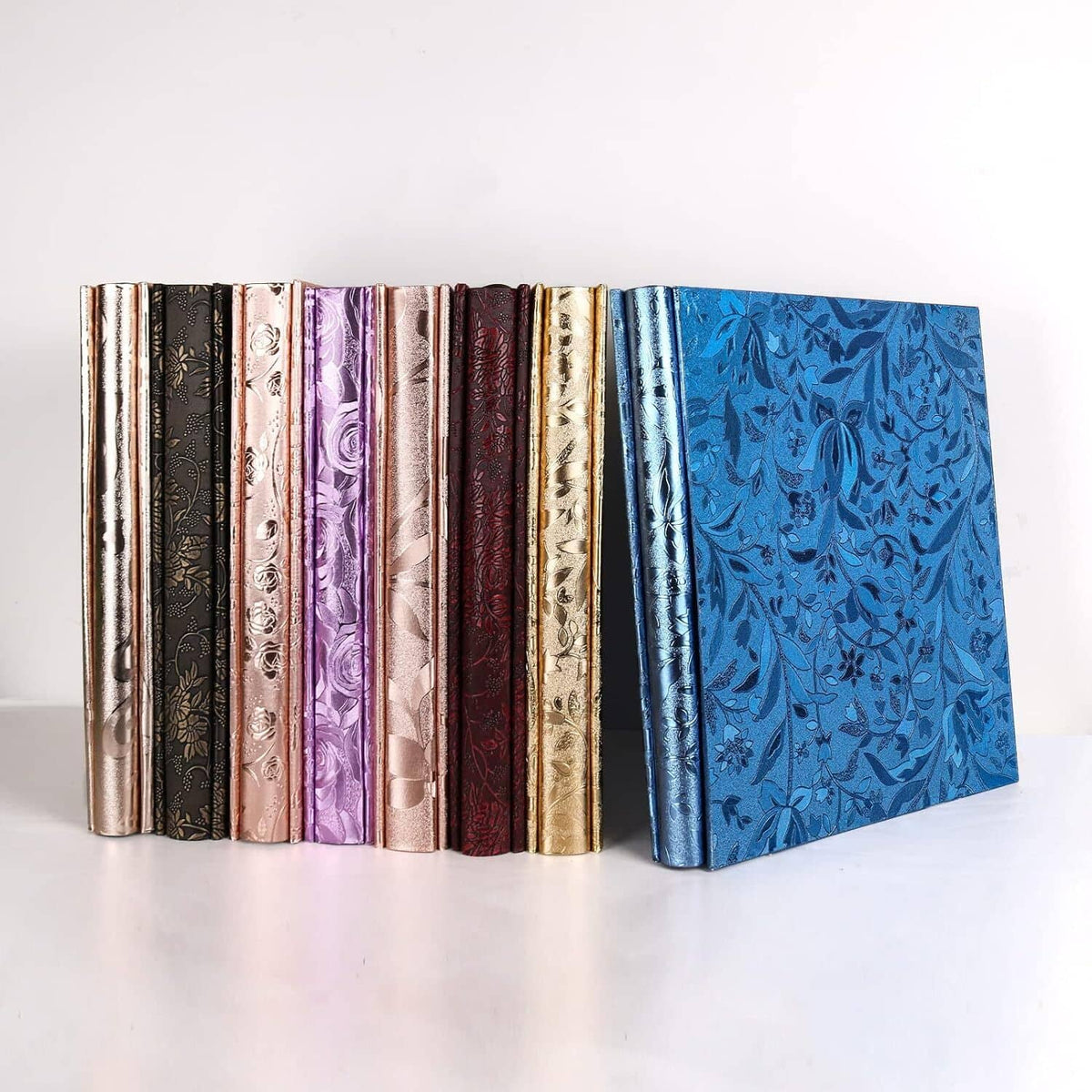 Assorted photo albums with metallic and floral covers, including blue.