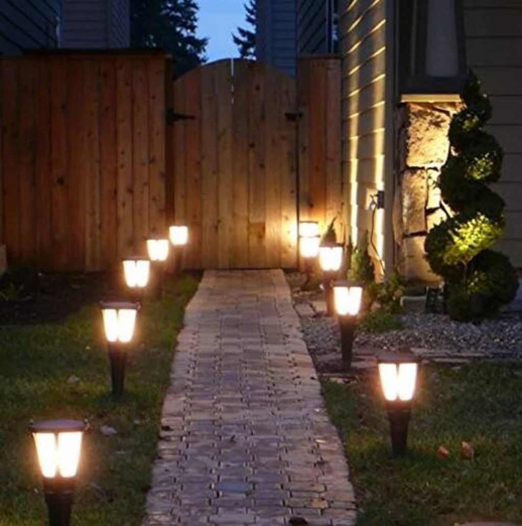 Outdoor walkway lights with square tops casting cool-white light through a yard.