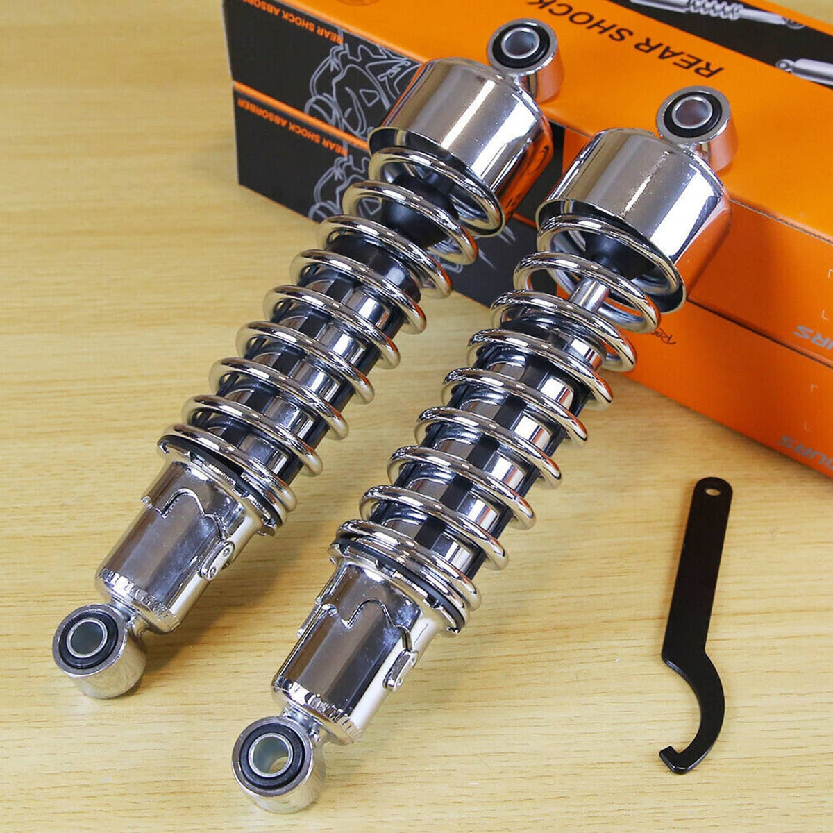 Pair of chrome rear motorcycle shocks with coil springs and black install tool