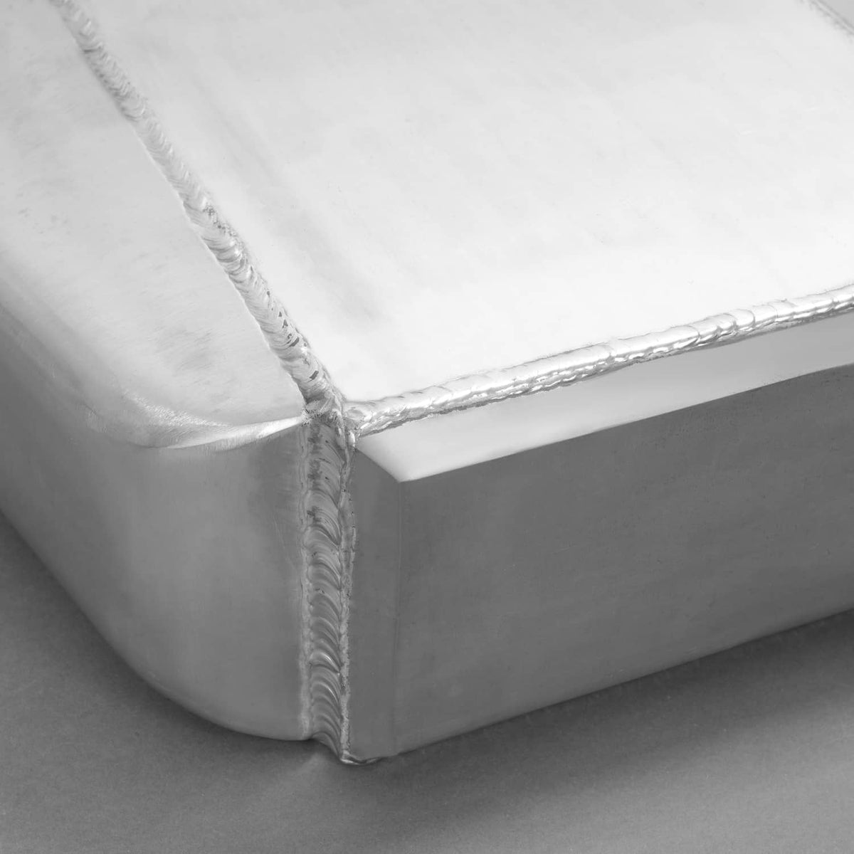 Close-up of welded aluminum intercooler corner with reinforced seam and tube edge