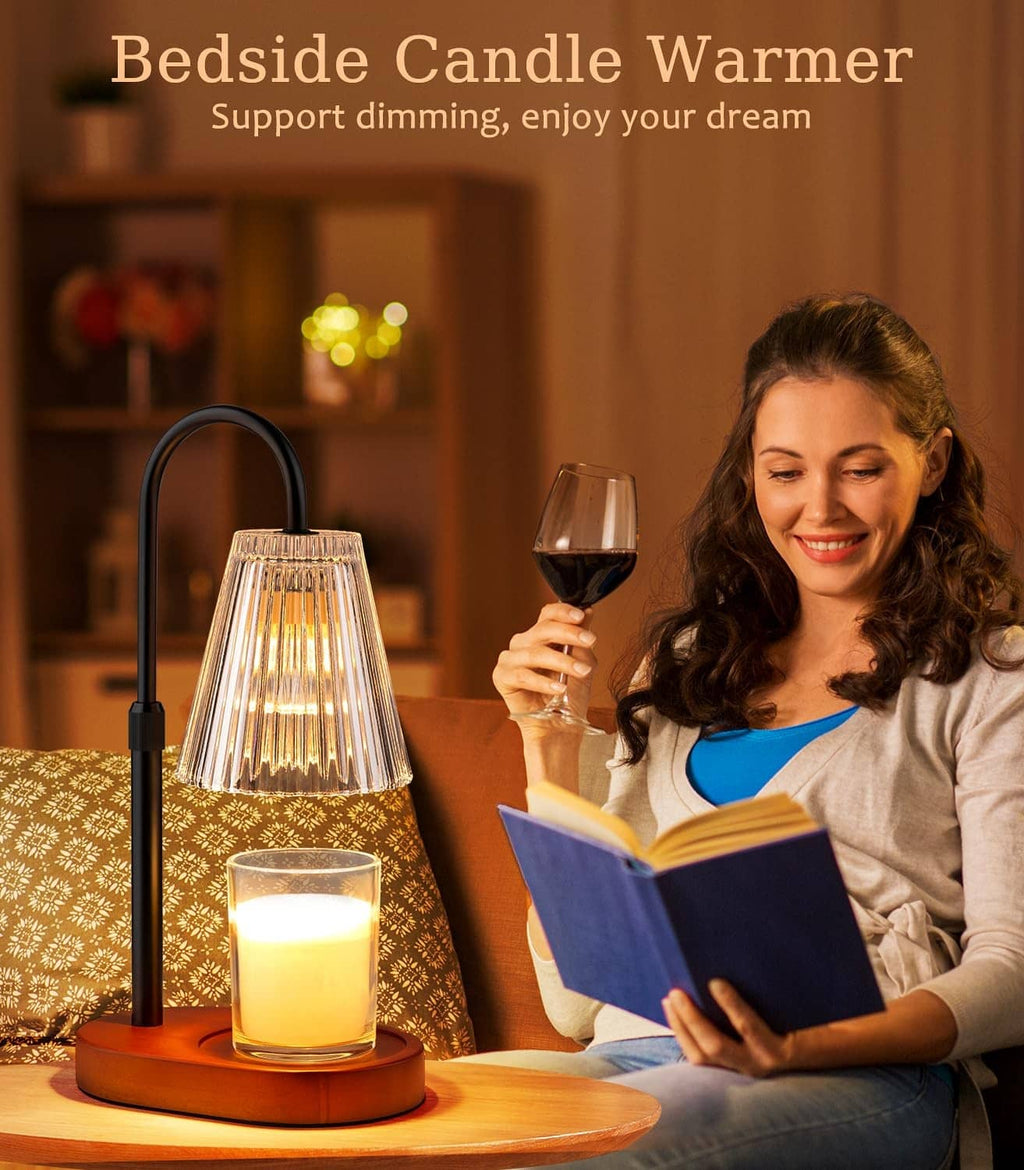 Candle warmer lamp with clear glass shade on wooden base, lit jar candle beside reading.