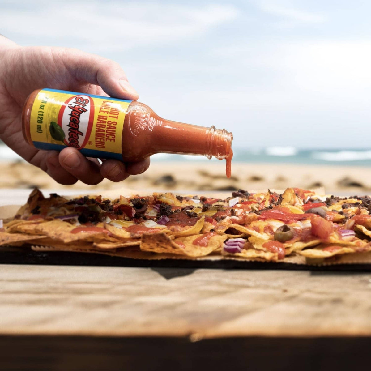 Red El Yucateco chile habanero hot sauce bottle being poured onto pizza